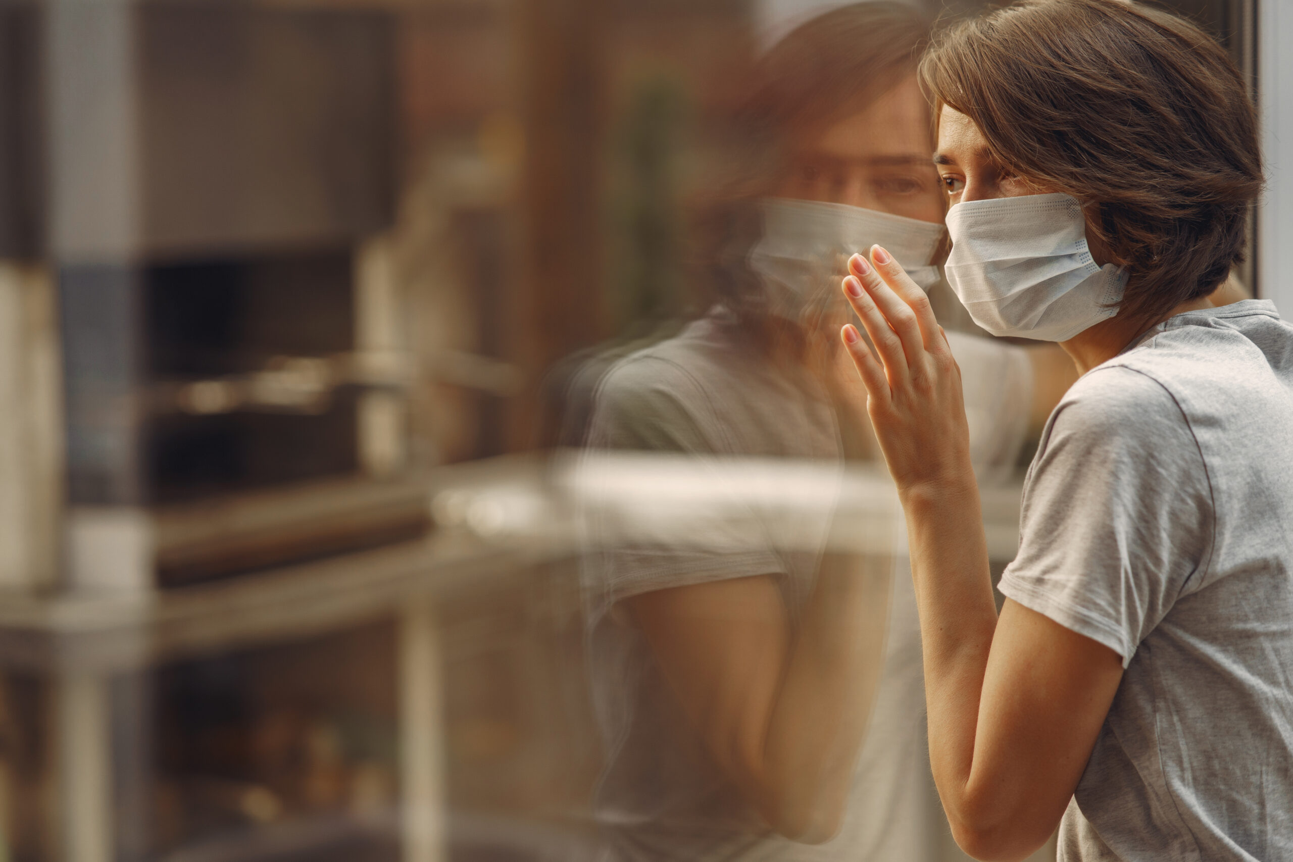 Mujer anciana con mascara coronavirus en una residencia mirando por la ventana